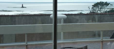 Un balcon avec vue sur la mer, un phare et une île lointaine.