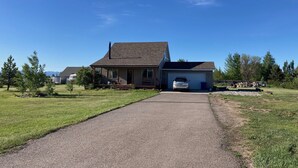Een gelijkvloers huis met een garage, een grindpad en een strakblauwe lucht.