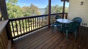 Un porche abrité avec une terrasse en bois, une table ronde et deux chaises.