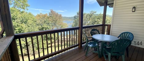 A covered porch with a wooden deck, a round table, and two chairs.