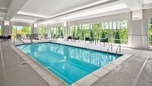 An indoor swimming pool with clear views of trees through large windows, surrounded by lounge chairs and a tiled floor. - TownePlace Suites by Marriott Asheville West (Asheville)