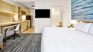 A hotel room with a large bed, a desk with a chair, a television, and a bathroom visible through an open door. - TownePlace Suites by Marriott Asheville West (Asheville)
