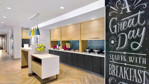 A modern kitchen with a central island, wooden cabinets, and a chalkboard sign saying "A Great Day Starts with Breakfast". - TownePlace Suites by Marriott Asheville West (Asheville)
