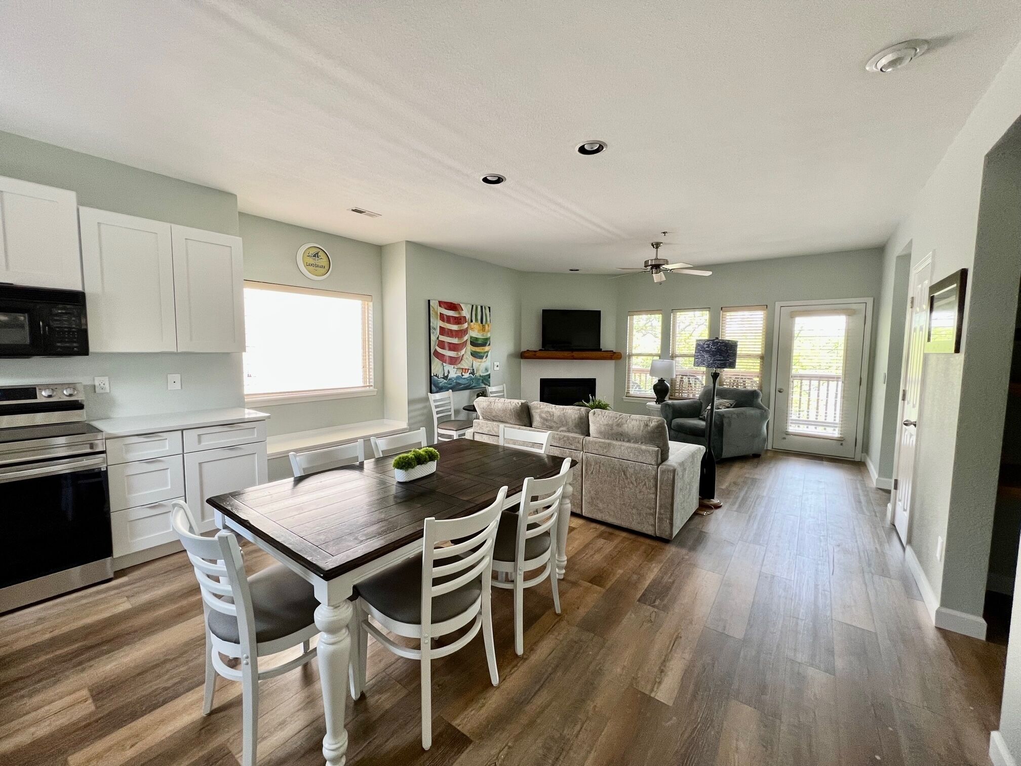A spacious kitchen with white cabinets, a wooden dining table, and a built-in microwave.