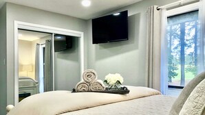 Een hotelkamer met een bed, een flatscreen televisie aan de muur en een raam met gordijnen.