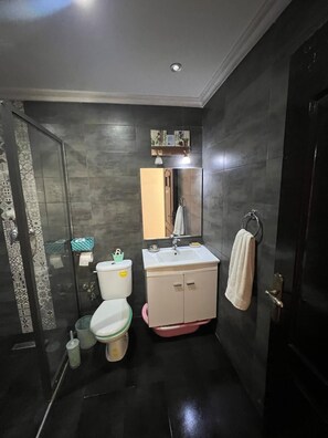 A compact bathroom with a toilet, sink, and shower. - Tres BEL Appartement Avec Piscine ET Parking A 10 MIN DE LA Plage D Agadir (Agadir)