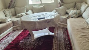 Ein Zimmer mit einer Sofagarnitur, einem Tisch mit Tischdecke und einem gemusterten Teppich.