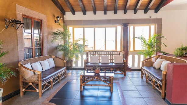 A spacious lobby with a wooden ceiling, large windows, and several seating areas with cushions and plants. - Casa Graciela Hotel Pátzcuaro (Patzcuaro)