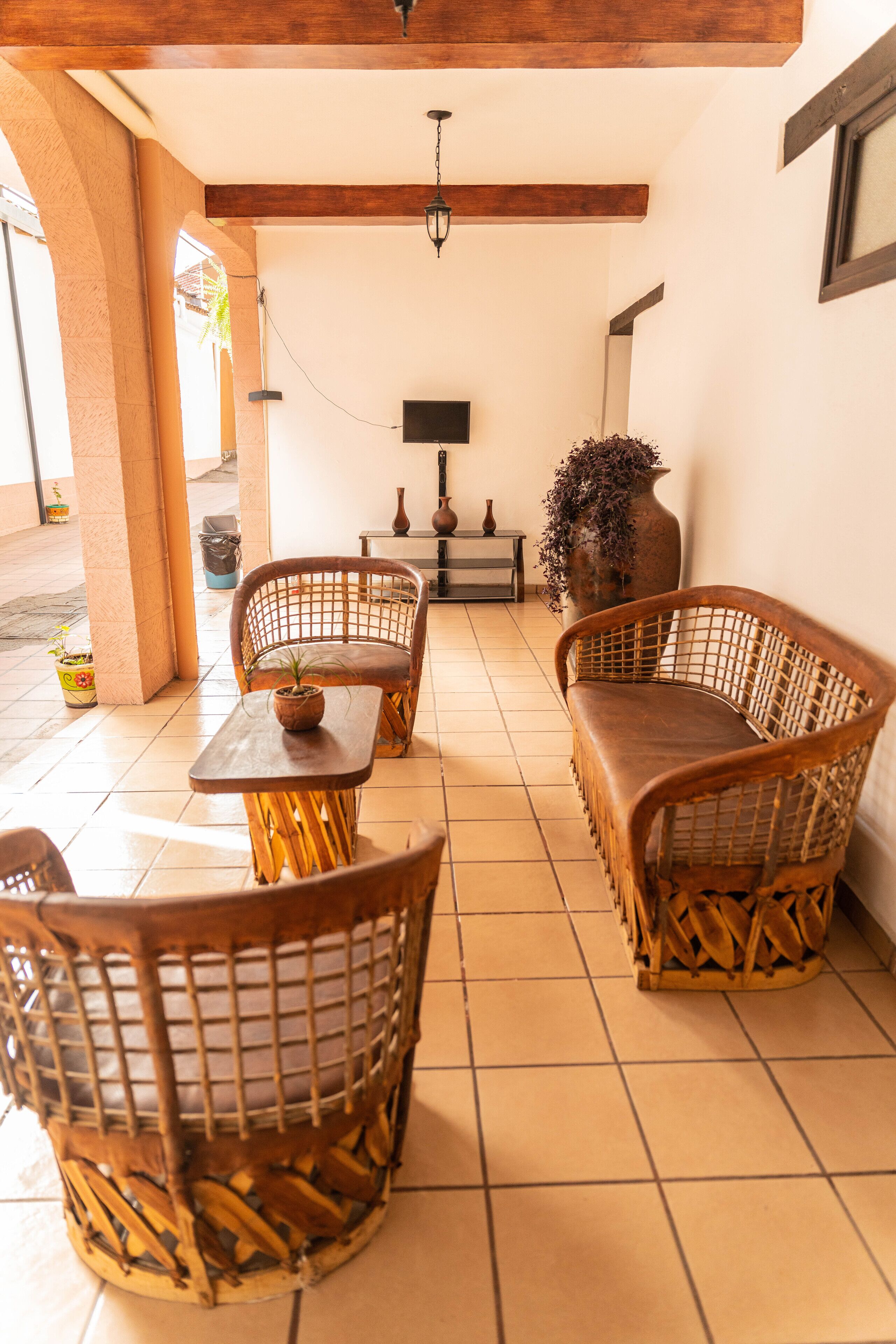 A covered patio area with wicker furniture, a table, and a potted plant.