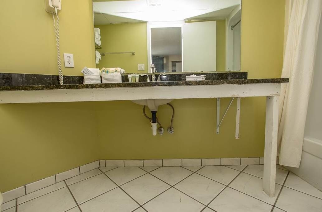 A bathroom with a white sink, a mirror, and a telephone on the wall.
