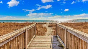 A wooden boardwalk leading to a beach with a clear sky. - Boardwalk 539 & 540 (Myrtle Beach)