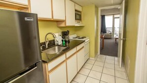 A compact kitchen with a refrigerator, stove, microwave, and sink. - Boardwalk 539 (Myrtle Beach)