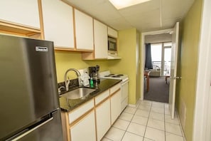 Una cocina compacta equipada con refrigerador, estufa, microondas y pileta.