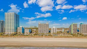 A beachfront hotel with multiple high-rise buildings, a sandy beach, and ocean waves. - Boardwalk 539 (Myrtle Beach)