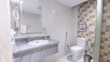 Une salle de bain avec un lavabo en marbre, des toilettes et une douche.