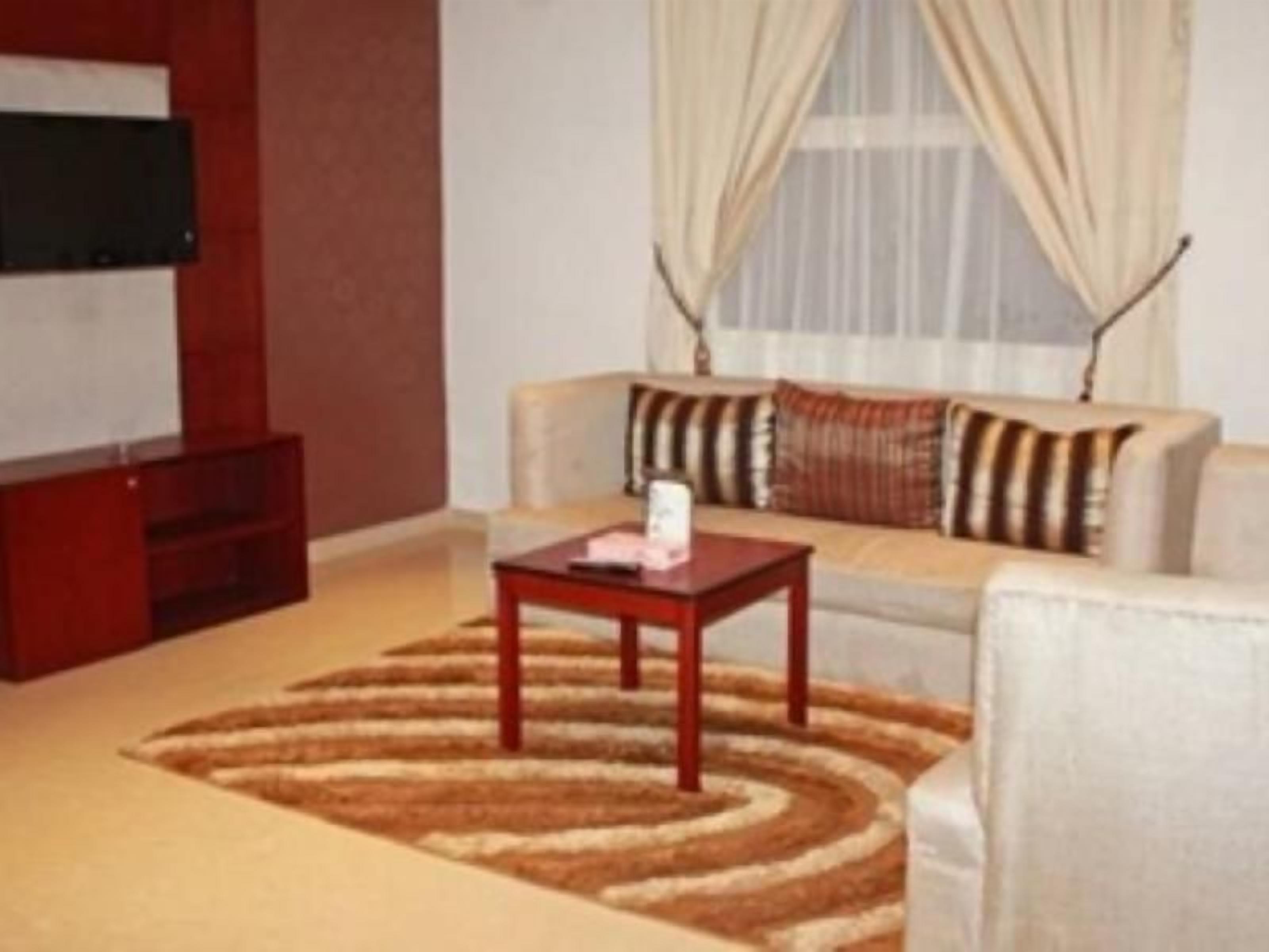 A living room with a sofa, a coffee table, and a flat-screen TV mounted on the wall.