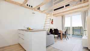 A modern, open-plan living space with a kitchen, dining area, and a balcony.