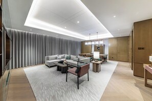 A modern living room with a sofa, coffee table, and dining area. - Hualuxe Xi an Chanba (Xi'an)