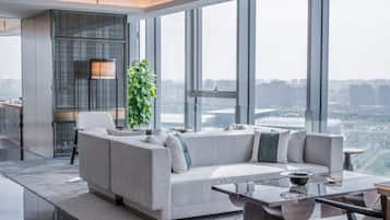 A modern living room with a sofa, a coffee table, and a view of a cityscape through large windows.