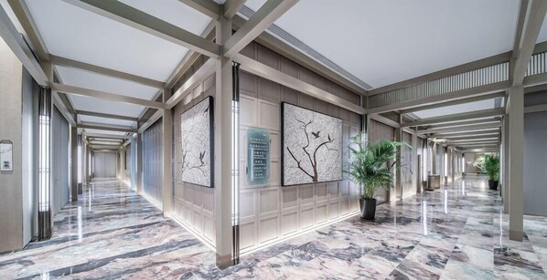 A long corridor with marble flooring, wooden paneling, and large wall art. - Hualuxe Xi an Chanba (Xi'an)