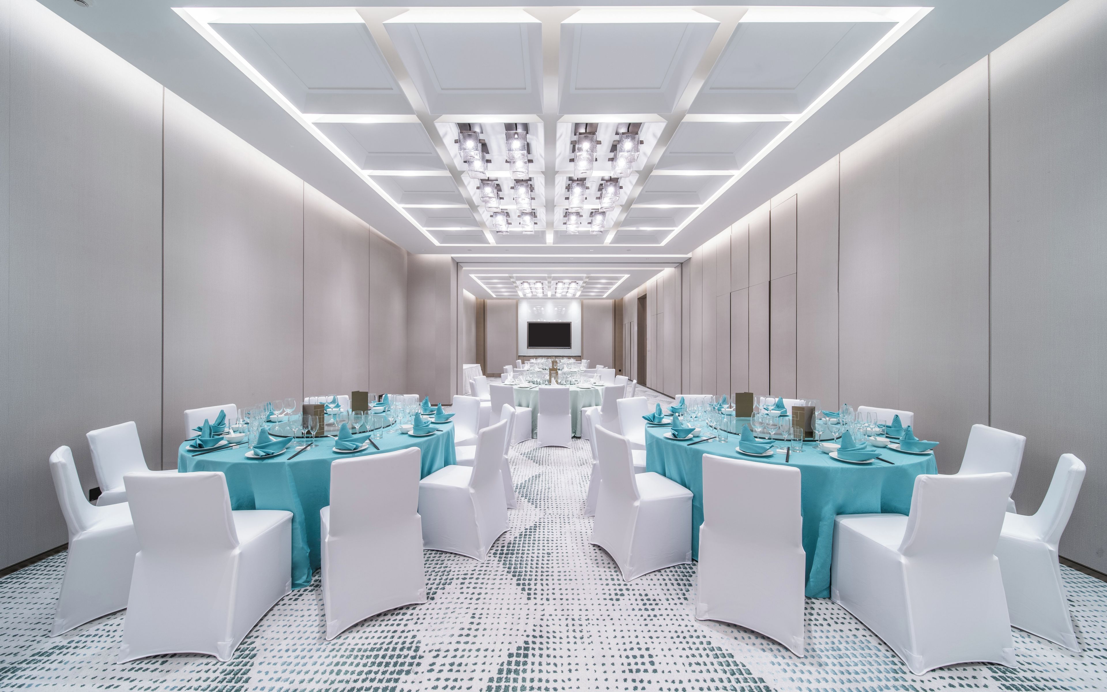 A conference room with a long table, white chairs, and teal tablecloths.
