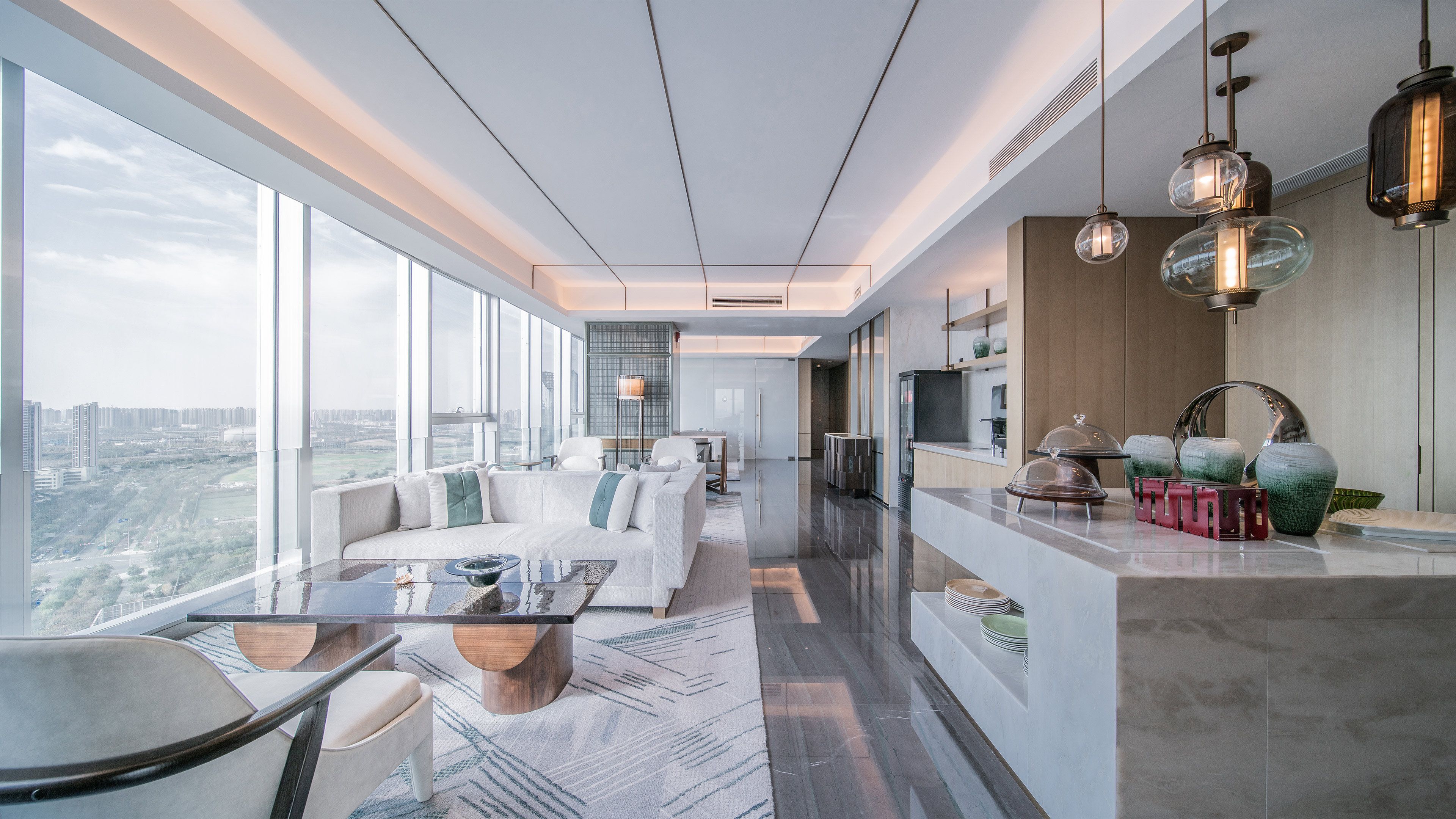 Un interior moderno con comedor, cocina y grandes ventanales que ofrecen vistas a la ciudad.