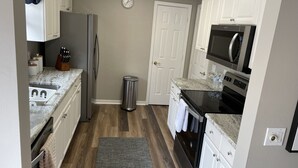 A compact kitchen with white cabinets, a stainless steel refrigerator, a microwave, and a sink. - When Quality & Location Matter (The Villages)
