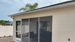 A house with a large sliding glass door leading to a patio area with a patio table and chairs. - When Quality & Location Matter (The Villages)
