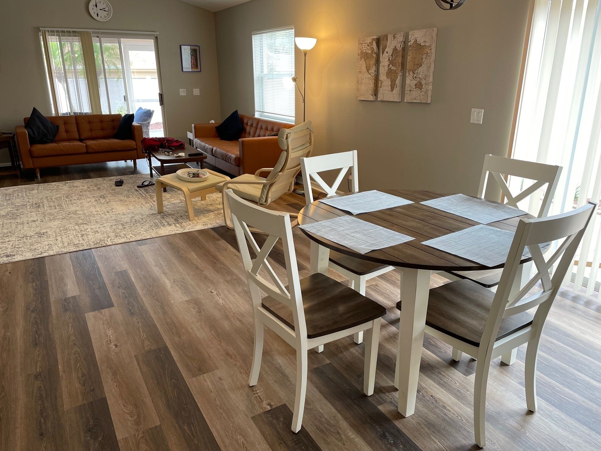 A modern living room with a wooden dining table, white chairs, a sofa, and a coffee table.