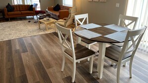 A modern living room with a wooden dining table, white chairs, a sofa, and a coffee table. - When Quality & Location Matter (The Villages)