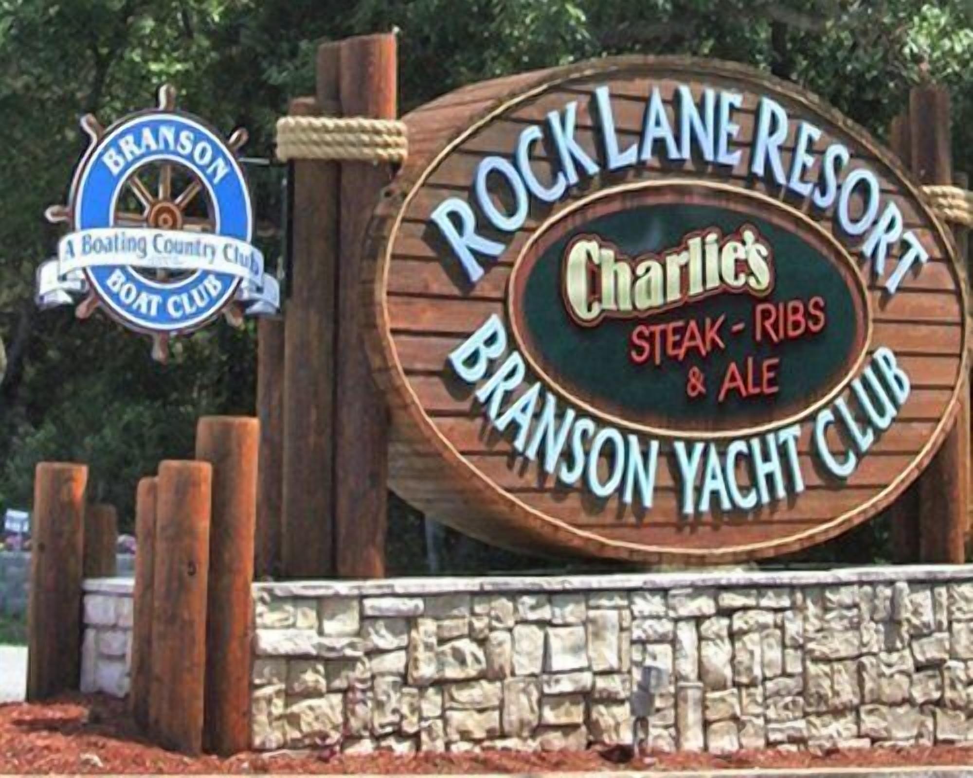 A wooden sign for Charlie's Steak-Ribs & Ale Club at Rock Lane Resort.