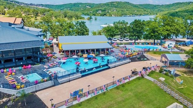 Un resort con varias piscinas, un área de estar techada y vistas a un lago.