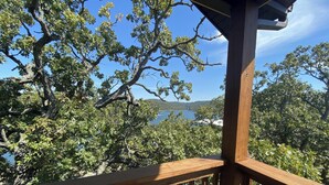 Una terraza de madera con vistas a un lago y árboles circundantes.