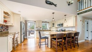 Une cuisine spacieuse dotée d’un grand îlot central, de planchers en bois et d’appareils électroménagers modernes.