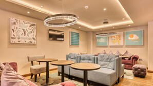 Een moderne lounge met banken, ronde tafels en decoratieve wandkunst.