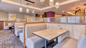 Een restaurant met zitjes, tafels en hangende lampen.
