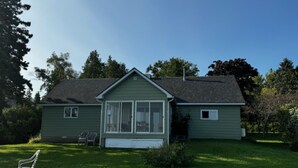 A single-story house with a front porch, a small attached garage, and a well-maintained lawn. - Beachfront Cabin on Straits of Mackinac  (Mackinaw City)