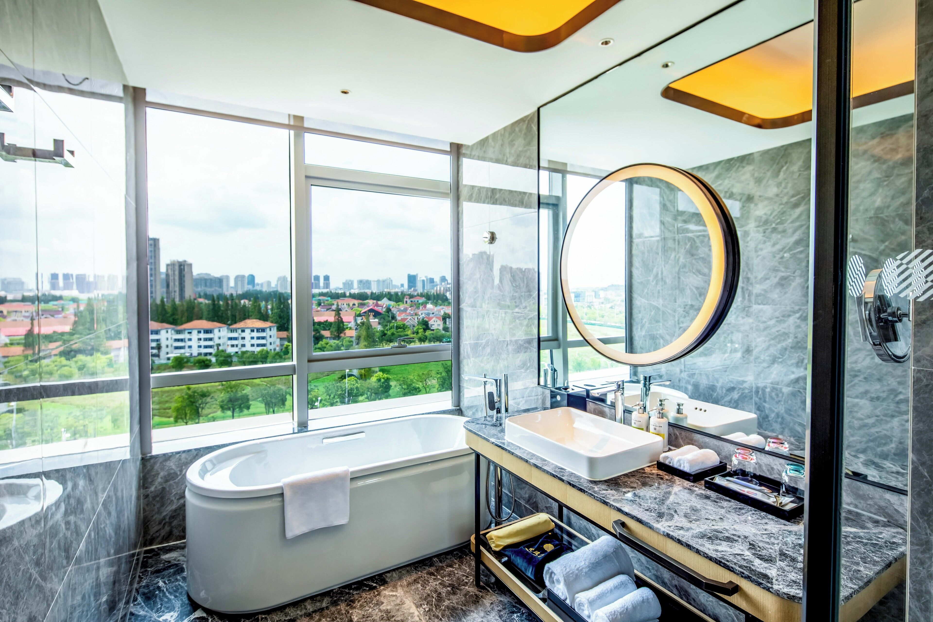 A modern bathroom with a bathtub, vanity, and large mirror.