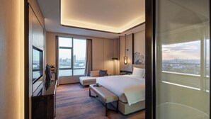 A modern hotel room with a large bed, a seating area, a desk, and a city view. - Pullman Suzhou Taicang  (Suzhou)
