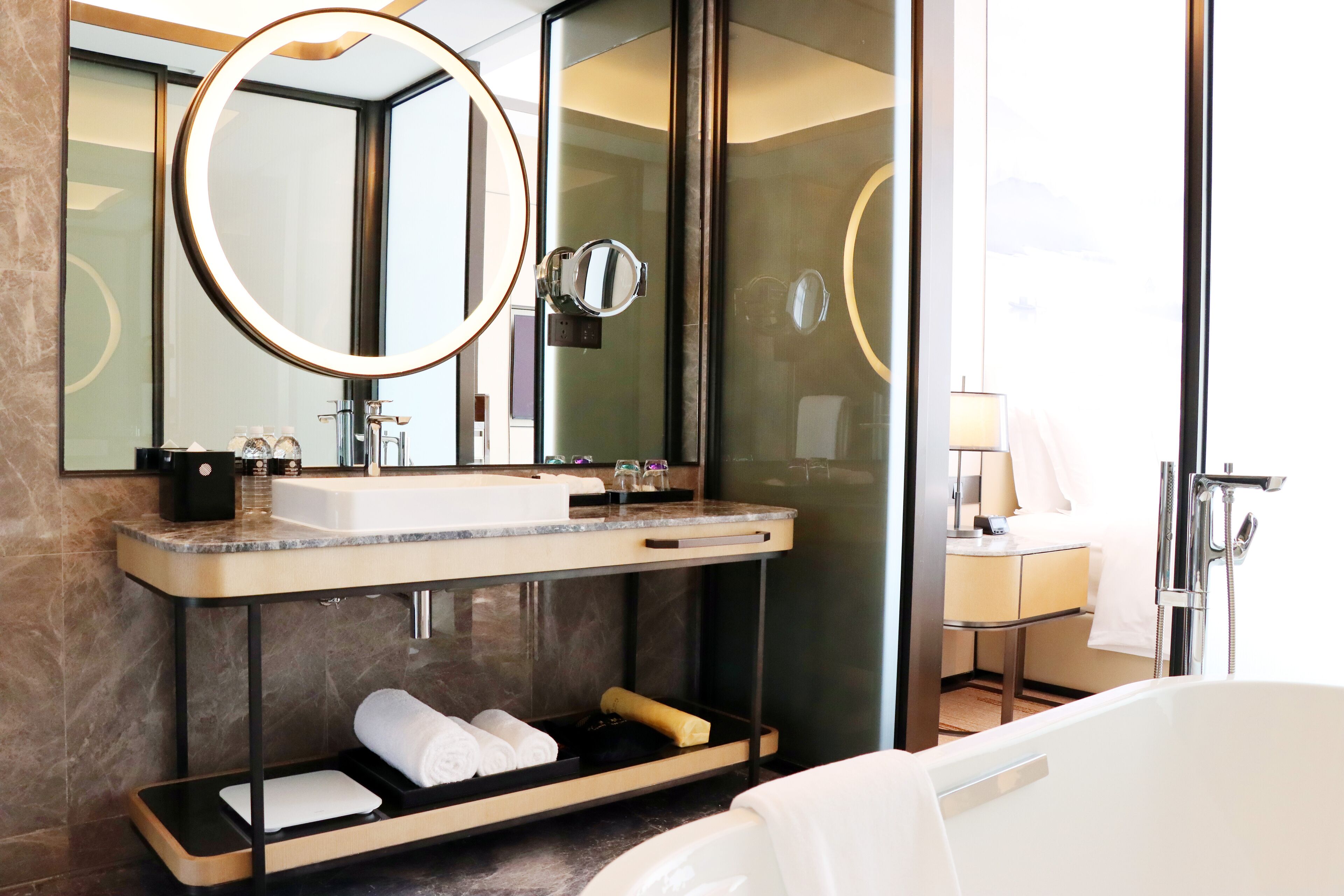 A modern bathroom with a large mirror, a sink, and a bathtub.