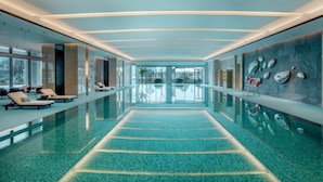 A modern indoor swimming pool with lounge chairs and a clear view of the outdoors. - Pullman Suzhou Taicang  (Suzhou)