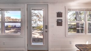 A room with a door leading to an outdoor area, a window with a view of a lake, and a sign on the wall.