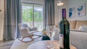 Un soggiorno moderno con un divano, un tavolino, una bottiglia di vino e un bicchiere.