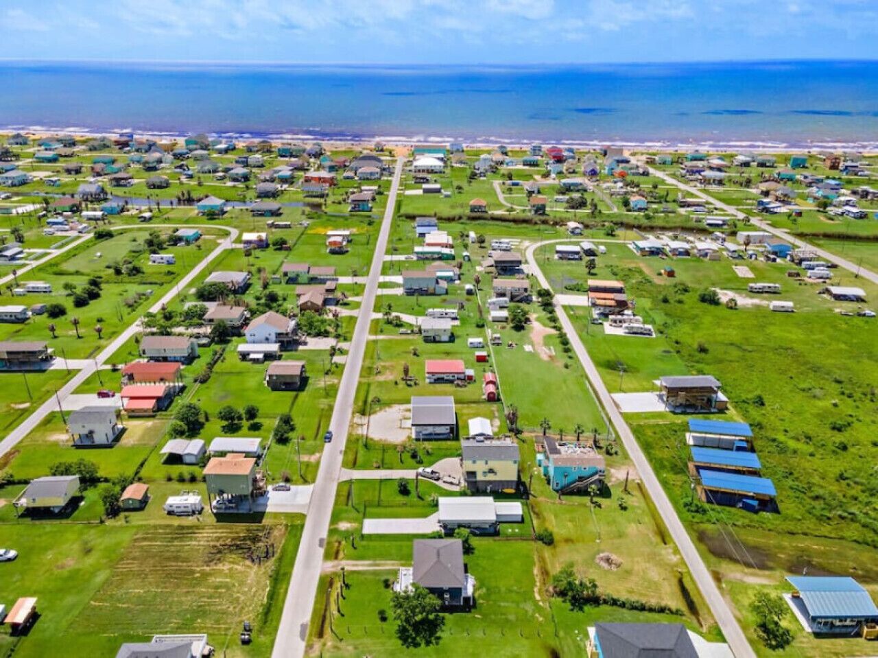 An aerial view of a residential area with houses, roads, and a coastline.
