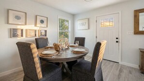 Un coin repas avec une table ronde, des chaises à revêtement gris et des œuvres d’art encadrées accrochées aux murs.