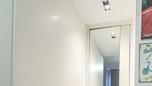 A narrow hallway with a bed in the background, a door on the right, and a small table in the foreground. - Pepezinho Ocean View (Rio de Janeiro)