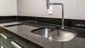 A modern kitchen with a stainless steel sink, black granite countertop, and built-in cabinetry. - Pepezinho Ocean View (Rio de Janeiro)