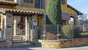 A two-story building with a stone facade, a balcony with a metal railing, and a small stone wall in front. - Casa nel Bosco con Sauna (Cervasca)