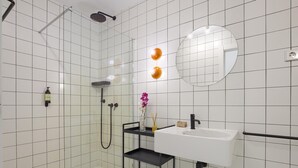 Une salle de bain moderne avec des carreaux blancs, une douche en verre, un lavabo blanc et un meuble-lavabo noir.