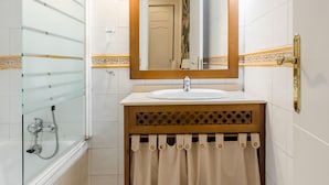 Een badkamer met een bad, een wastafel, een spiegel en een douche.